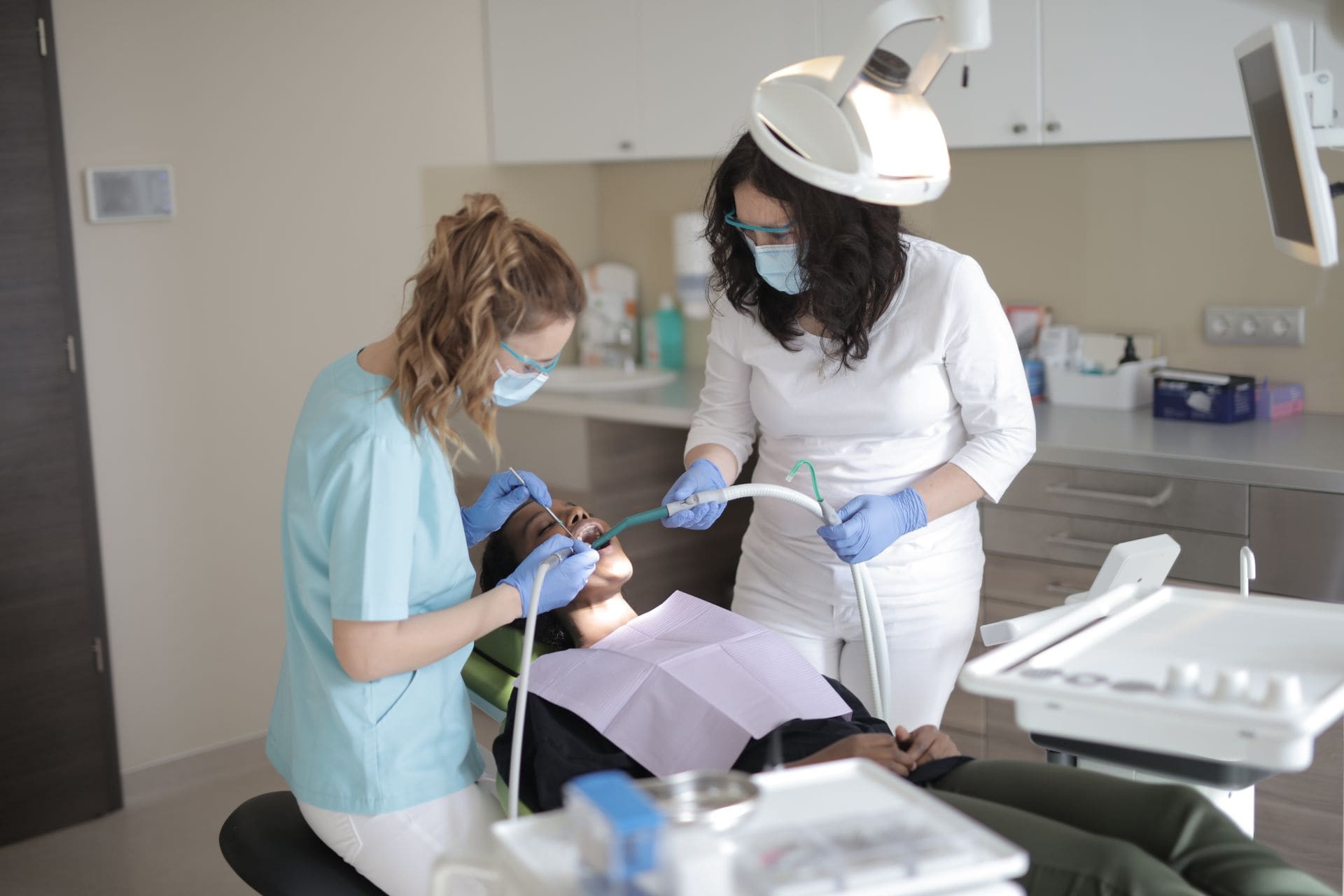 A dentist and her assistant treating a patient in a bright Pearl treatment room