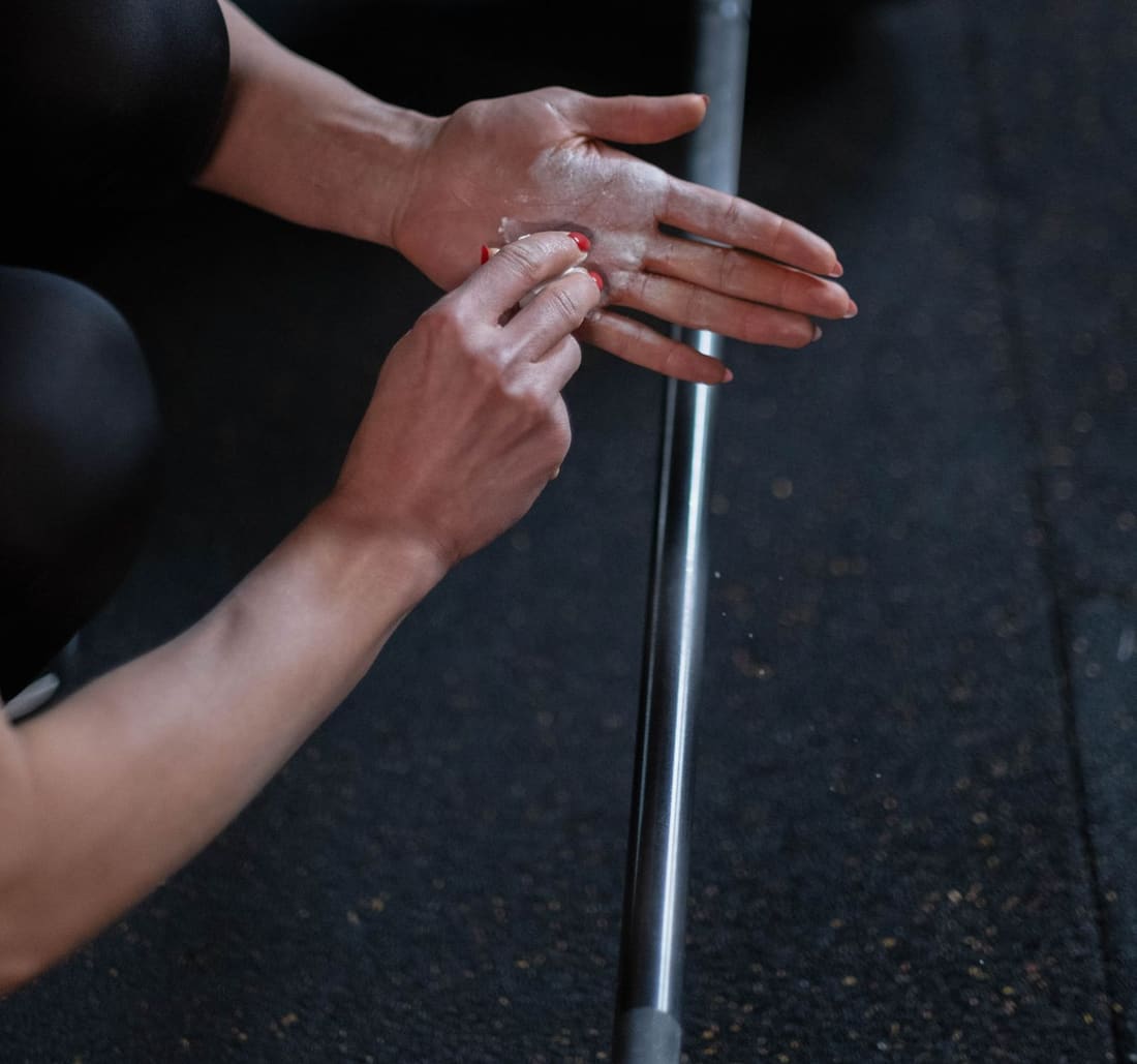 Hands being chalked over a loaded bar lying on the floor, seen from above