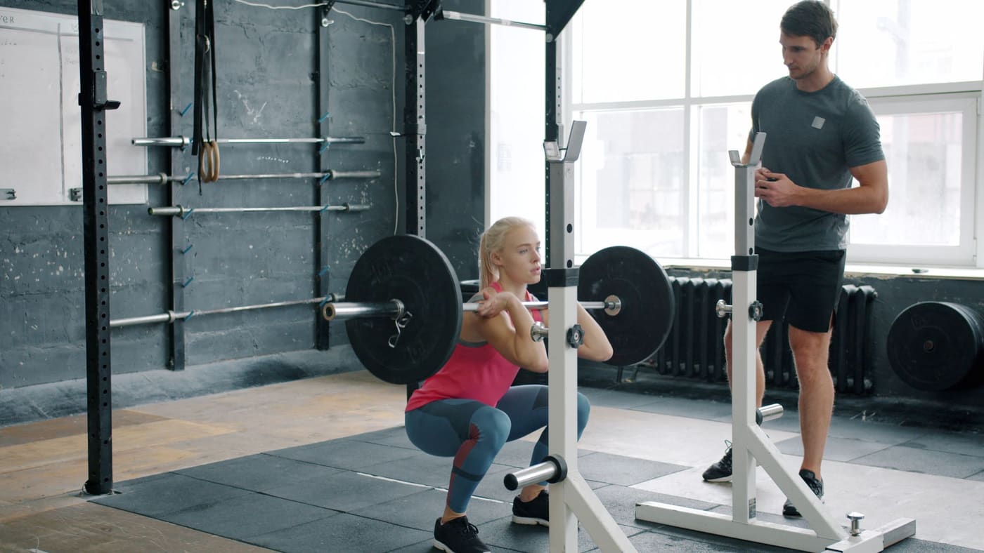 A back squat out of the stands with a coach watching from the next platform