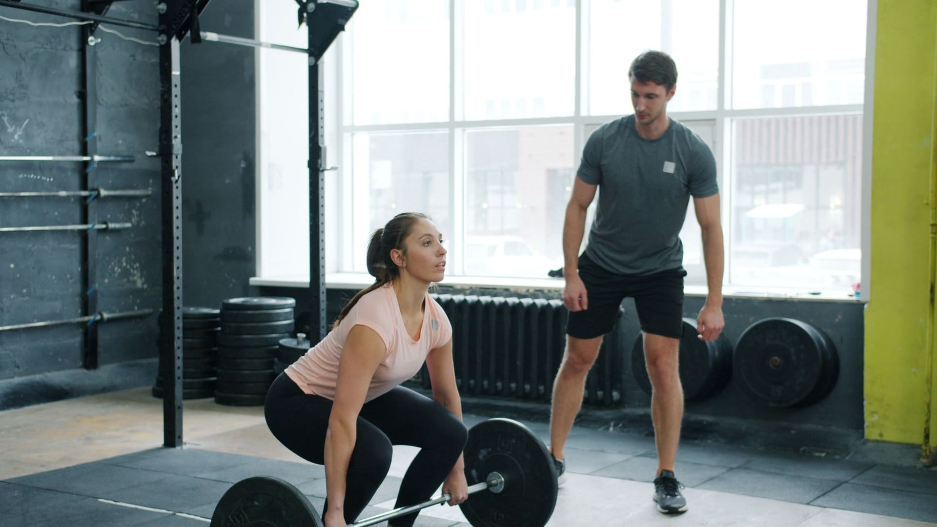 A coach watching a member set up a deadlift on the platform at Ironworks, Tradeston