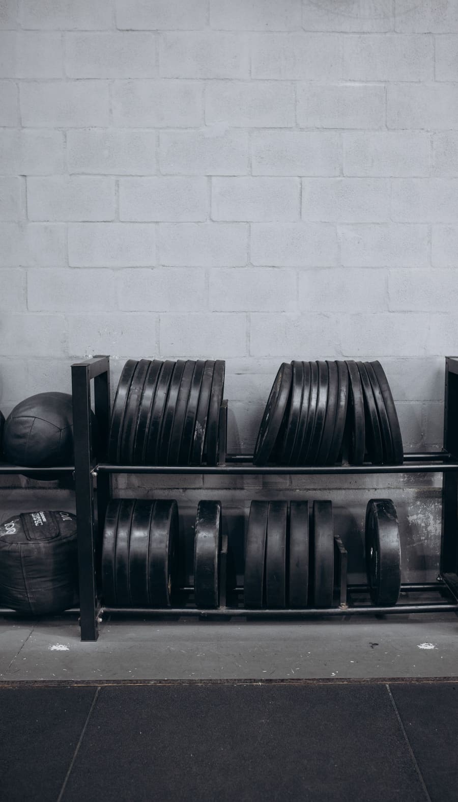 Bumper plates and medicine balls racked against the painted blockwork of the arch