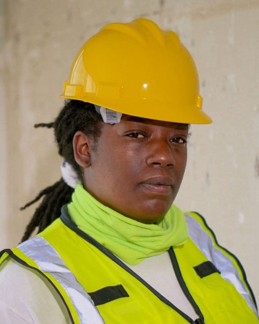 Technician in a hard hat and hi-vis holding a pipe wrench on site