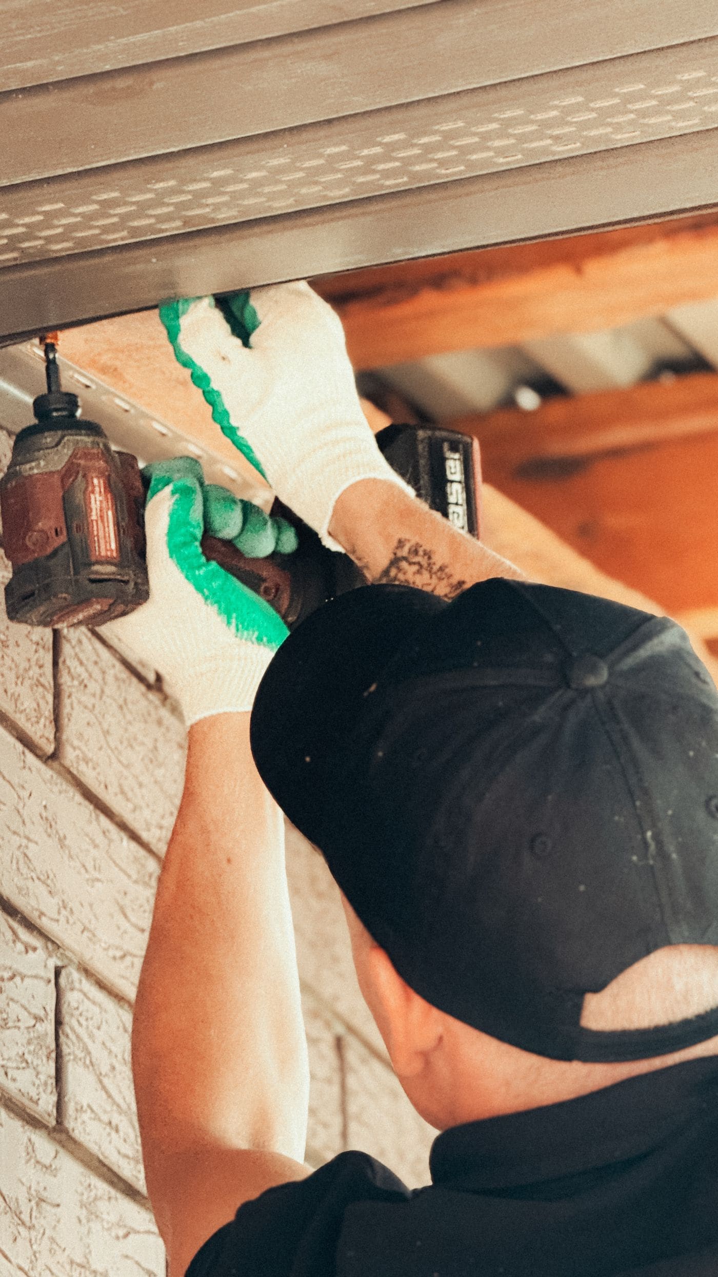 Handyman working under a soffit with a cordless drill