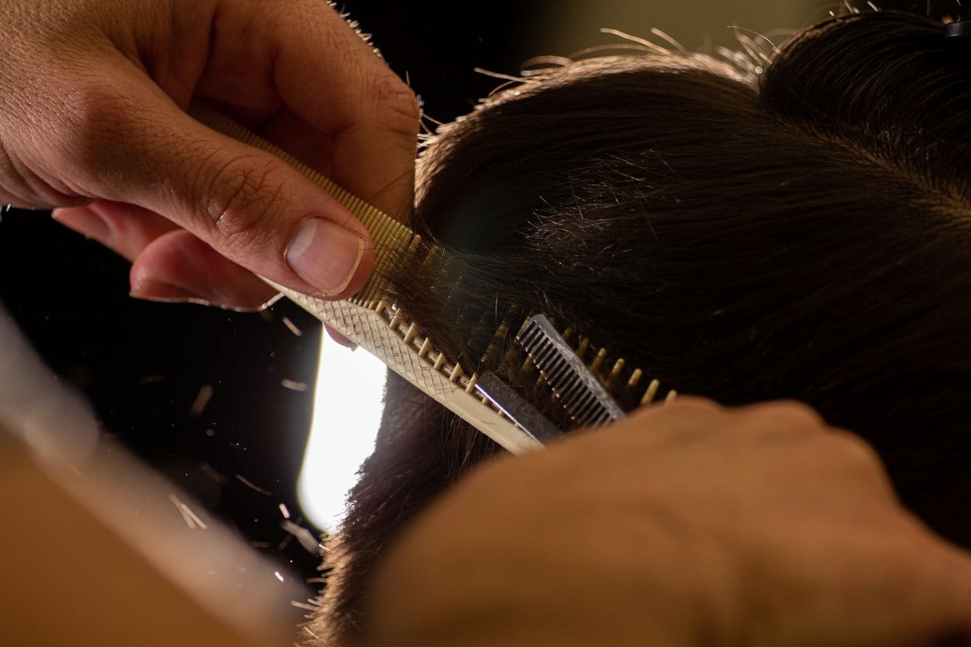 Stylist trimming hair with comb and scissors